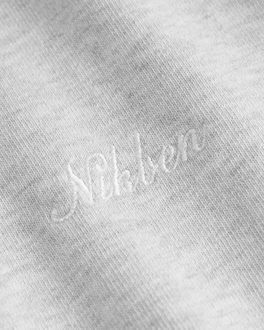 Close up of Nikben script logo embroidery on a grey hoodie