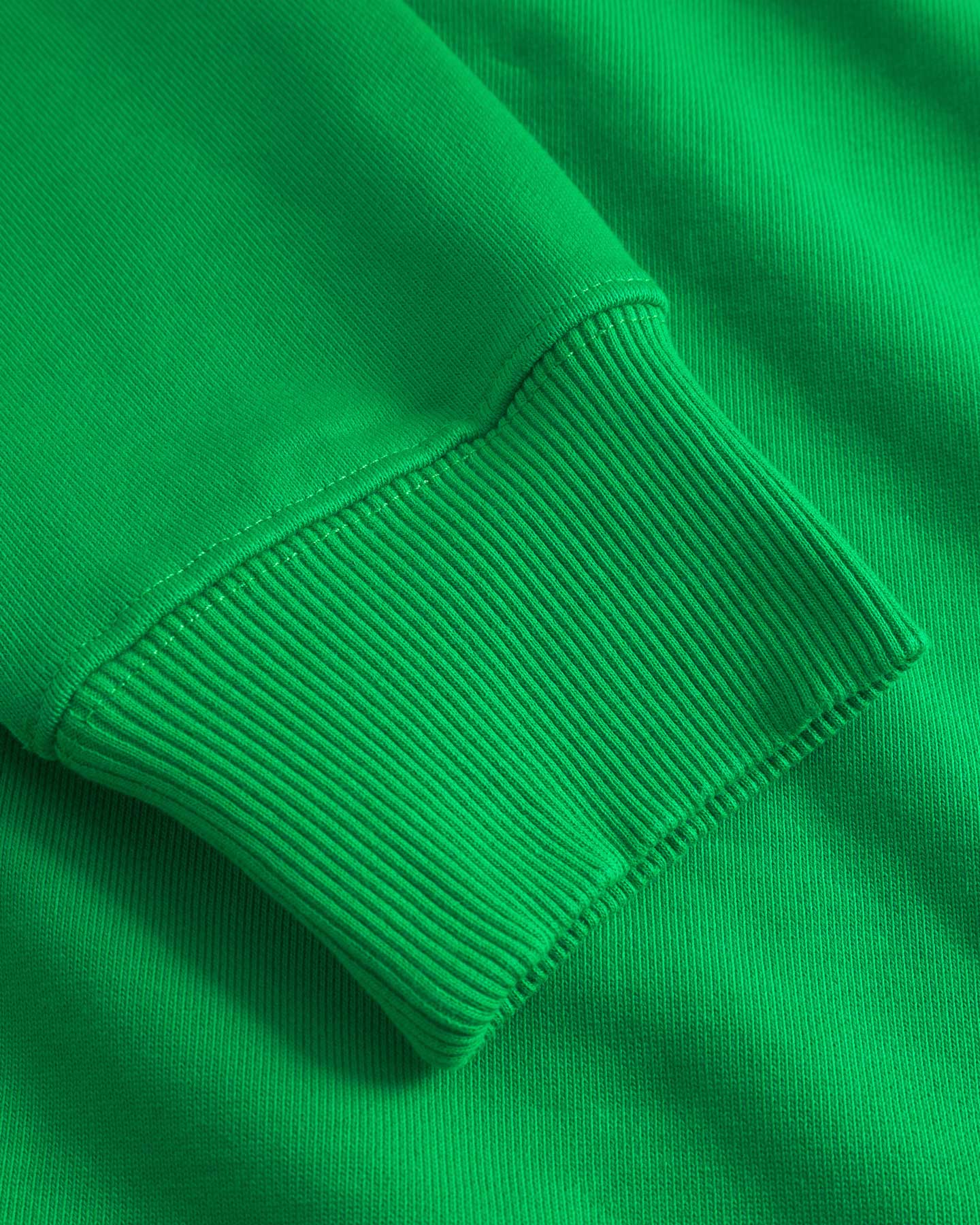 Close up of ribbed cuffs and stitchings on a green sweatshirt