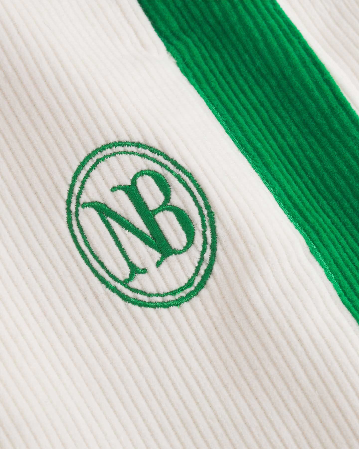 Close up of NB embroidery on white and green corduroy track suit pants 