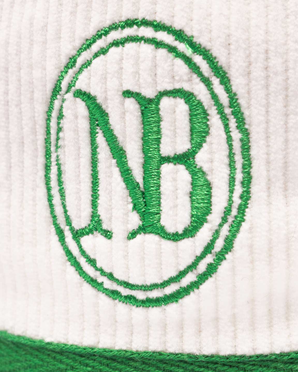 Close up of green NB embroidery on a white and green corduroy bucket hat 