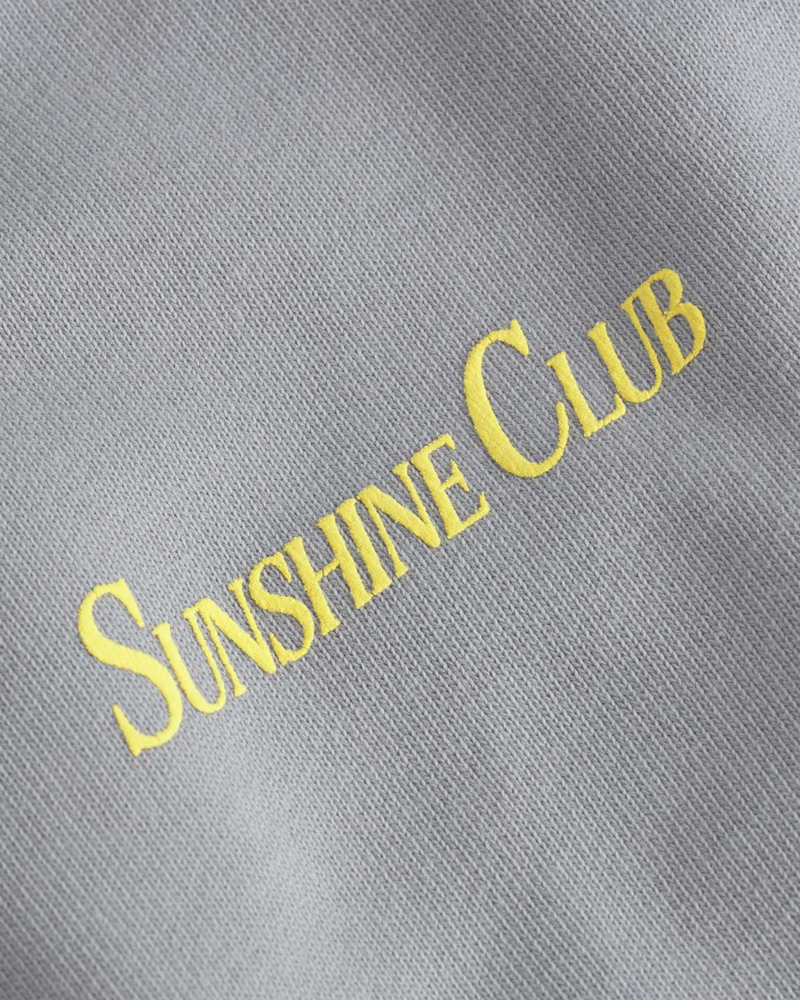 Close up of yellow sunshine club print on a grey hoodie