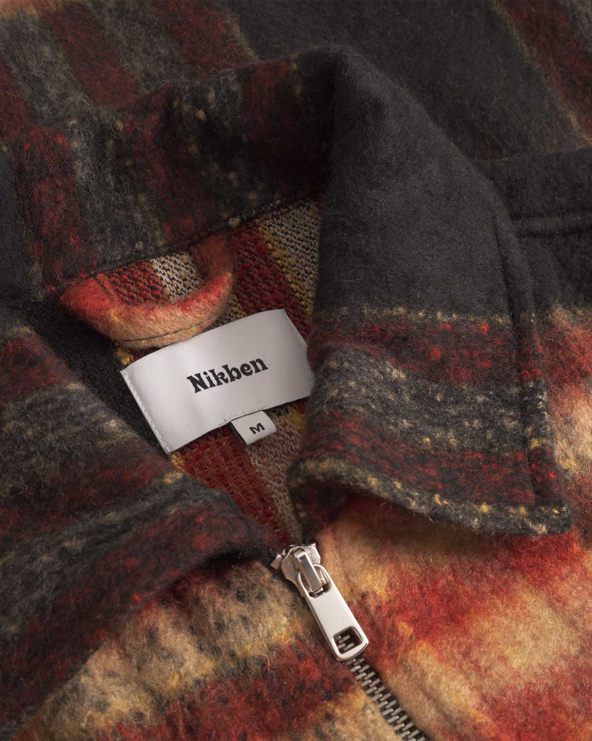 Close up of collar on an orange red colored lumberjack jacket with pockets, full zipper and embroidered Nikben logo 