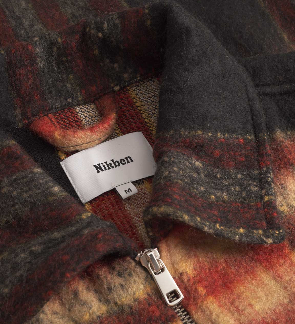 Close up of collar on an orange red colored lumberjack jacket with pockets, full zipper and embroidered Nikben logo 
