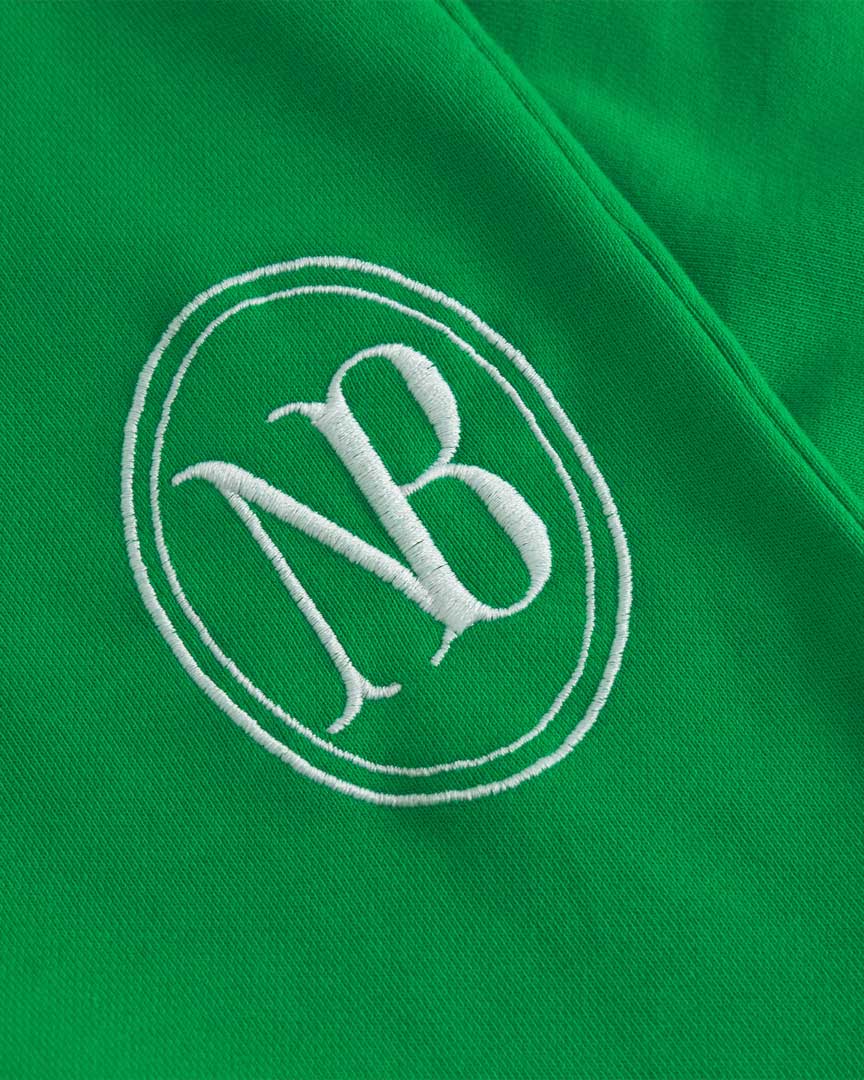 Close up of embroidered NB logo on green sweat pants