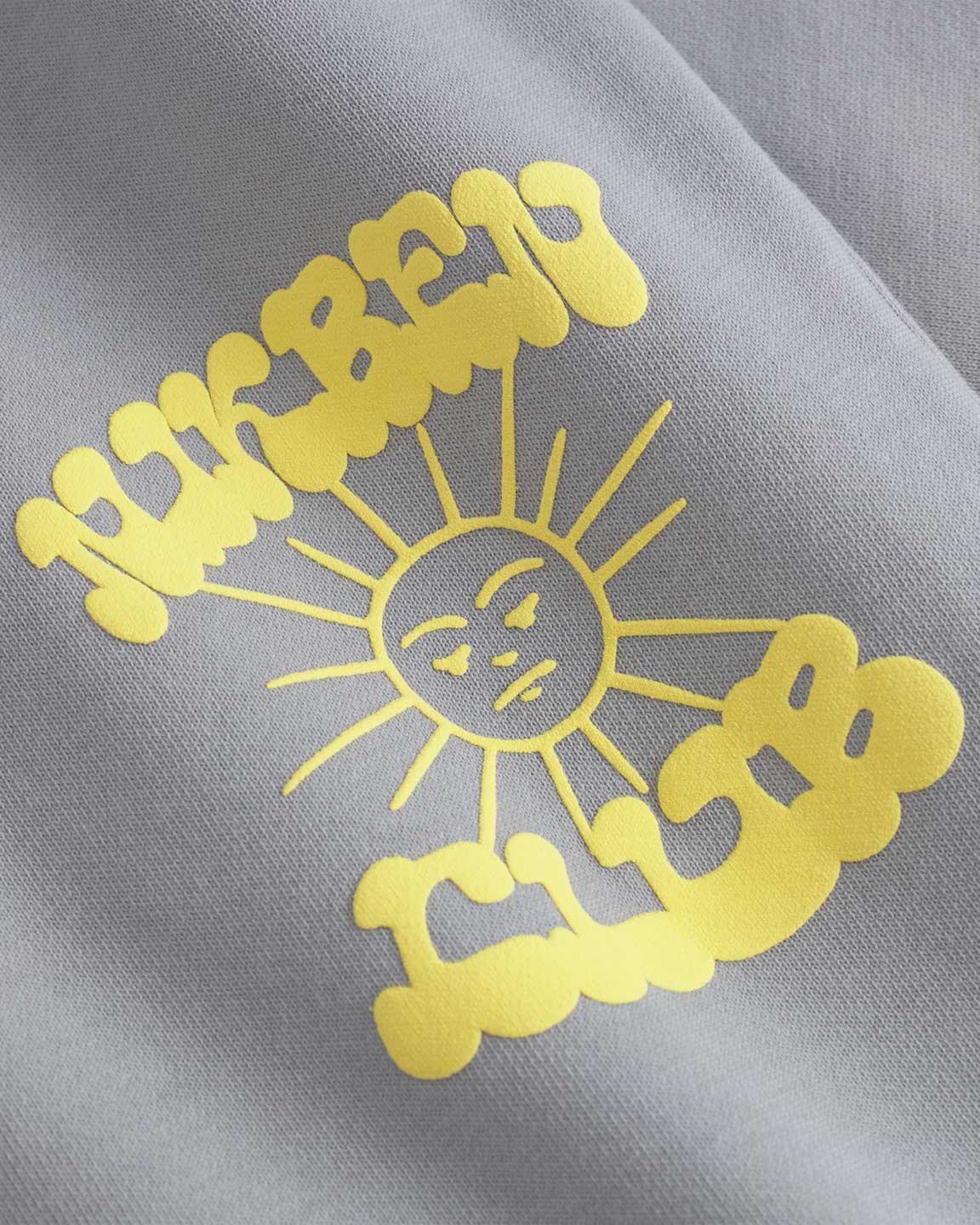 Close up of yellow Nikben Sunshine Club Print on grey sweat pants