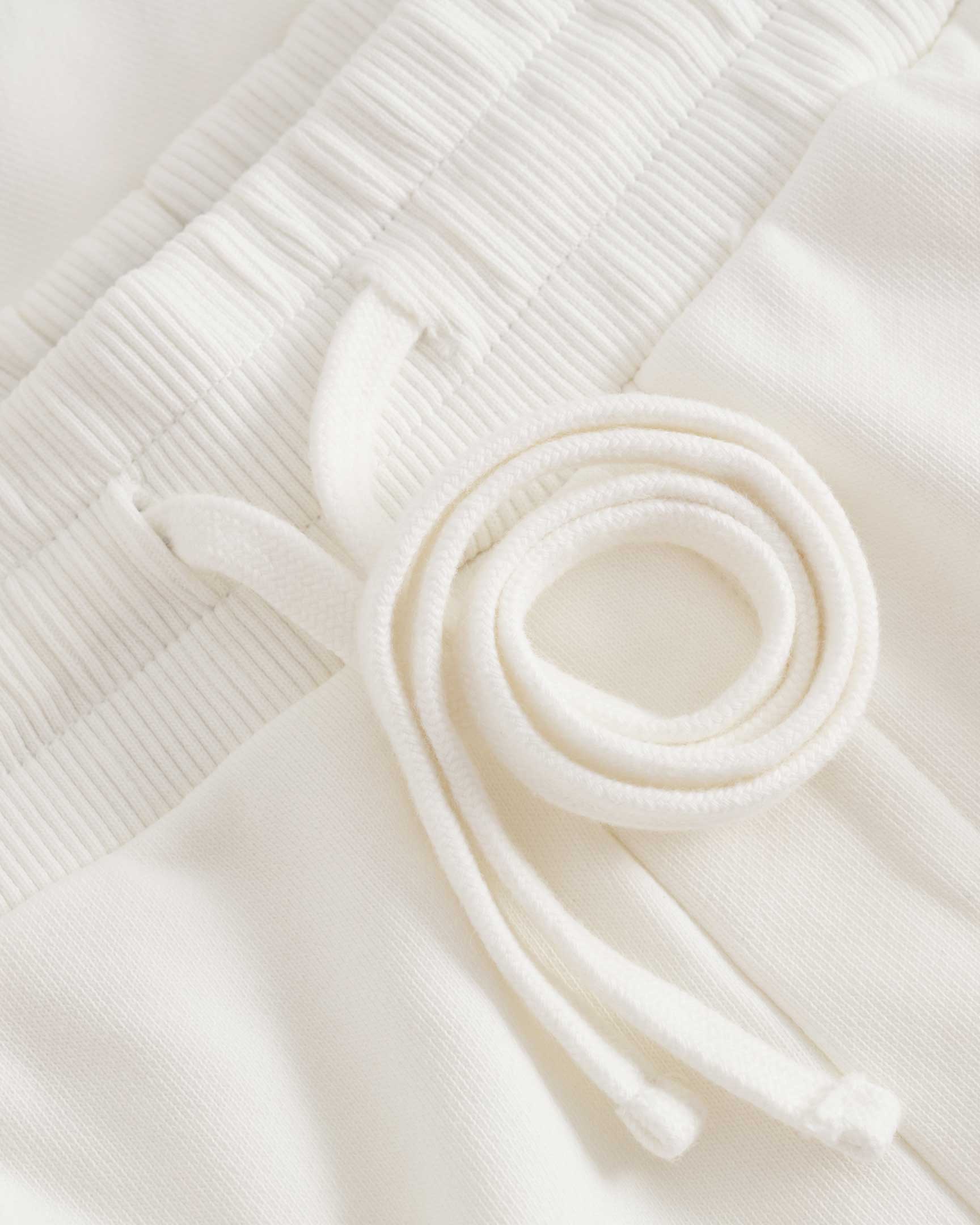 close up of drawstrings on white jersey shorts 