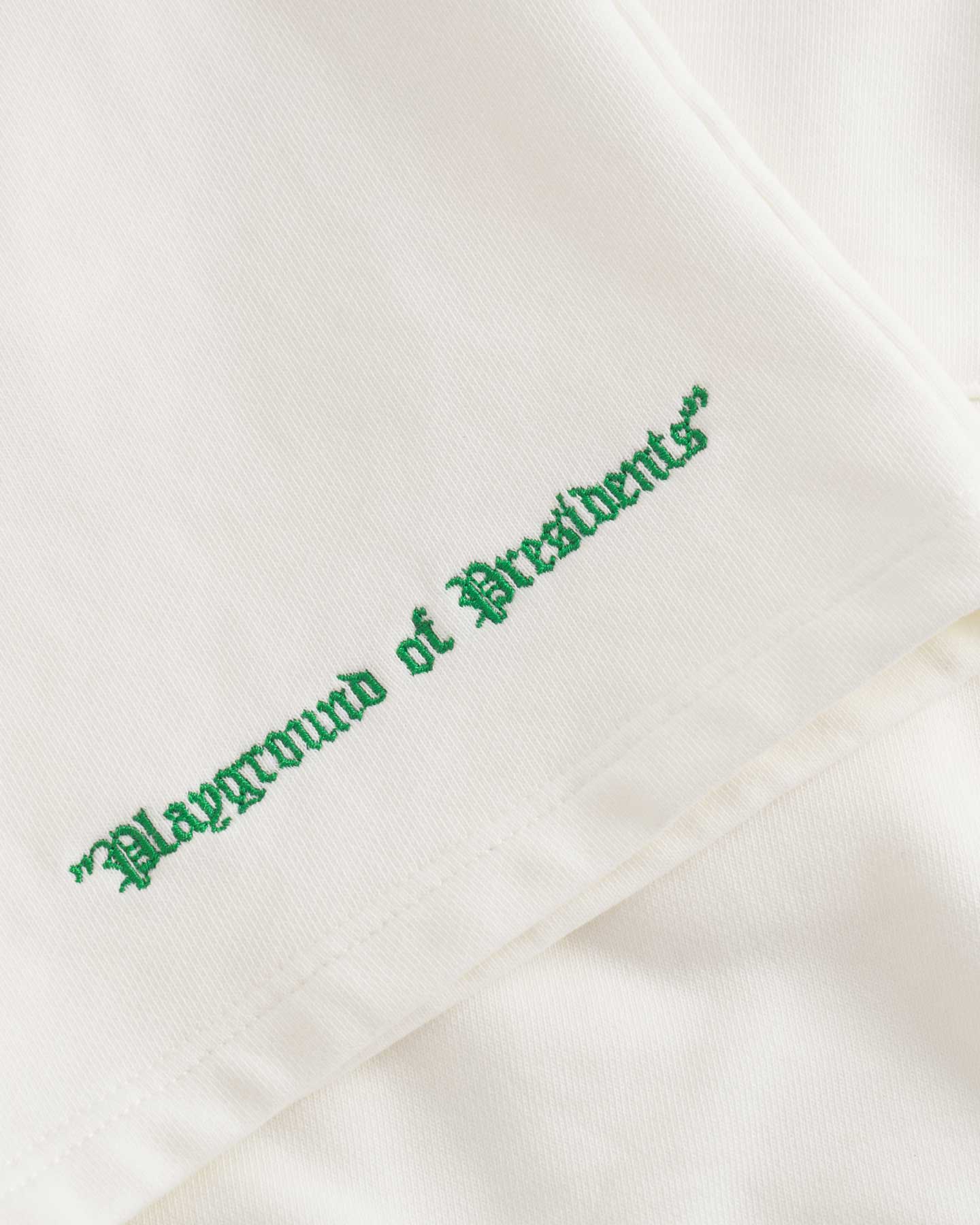 Close up of green embroidery on white jersey shorts