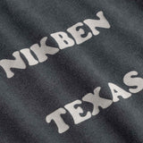 Close up of Text 'NIKBEN TEXAS' printed on black fabric.