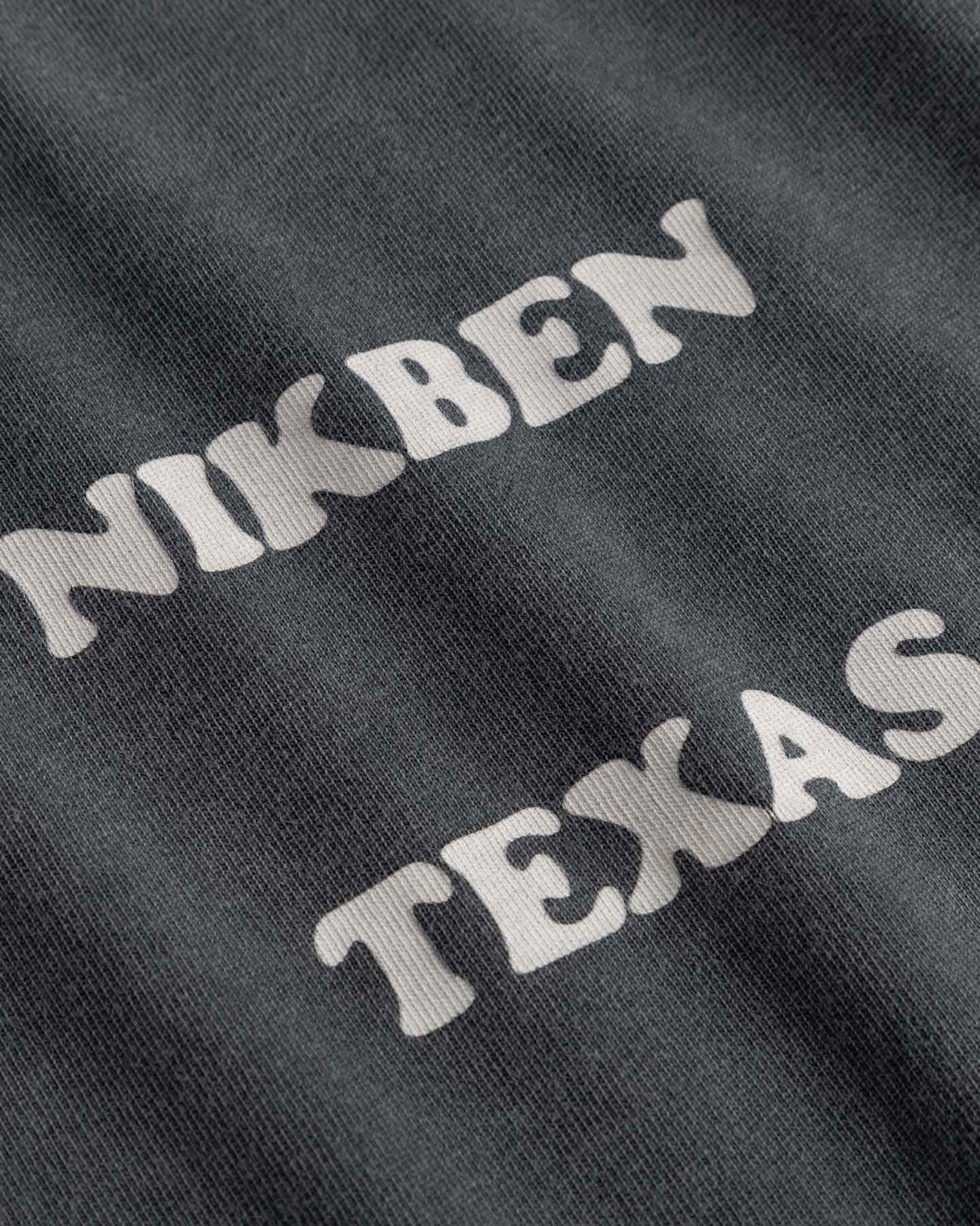 Close up of Text 'NIKBEN TEXAS' printed on black fabric.