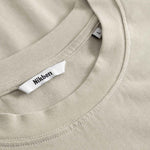 Close-up of a beige t-shirt with a brand label on the collar.