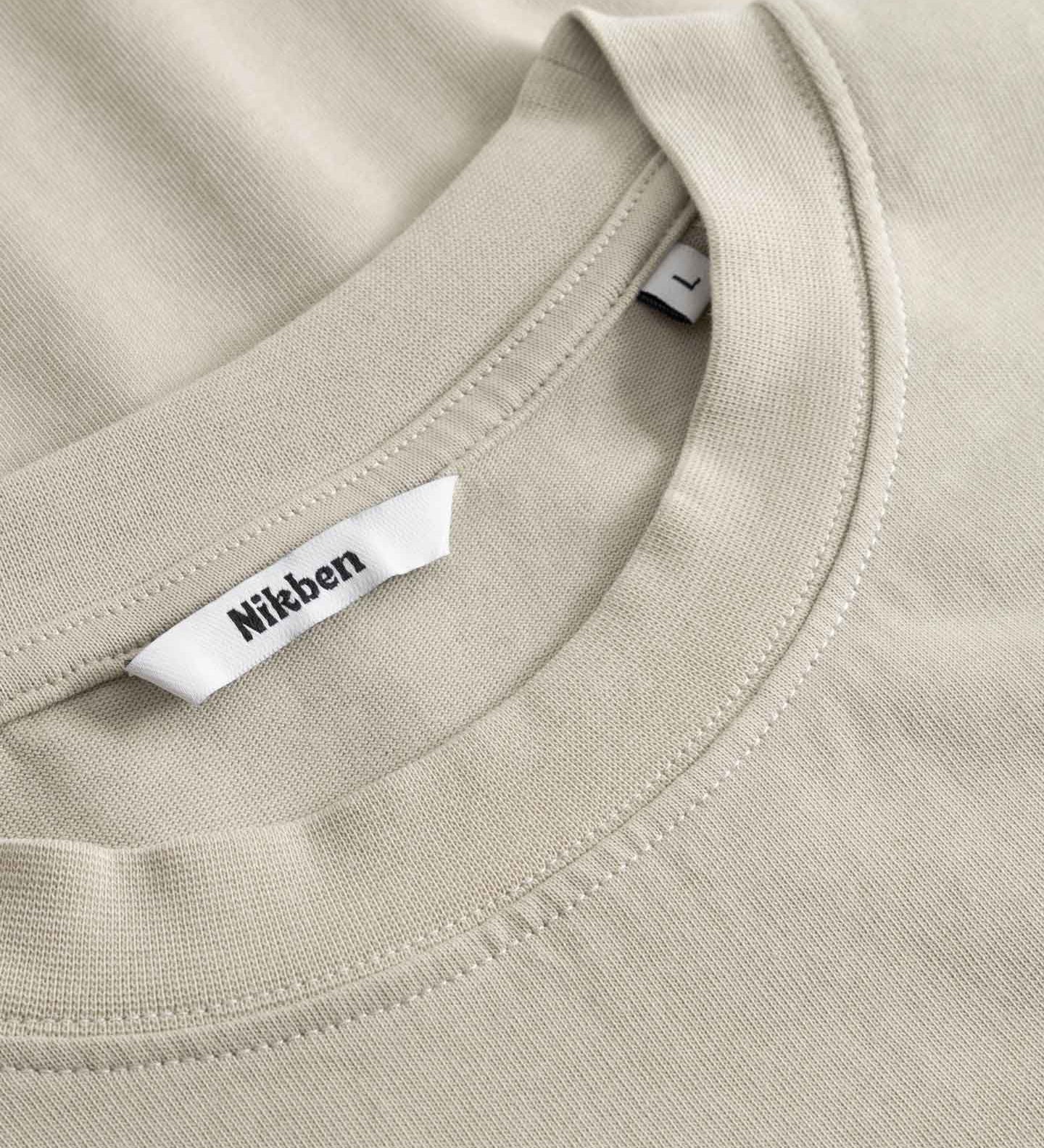 Close-up of a beige t-shirt with a brand label on the collar.