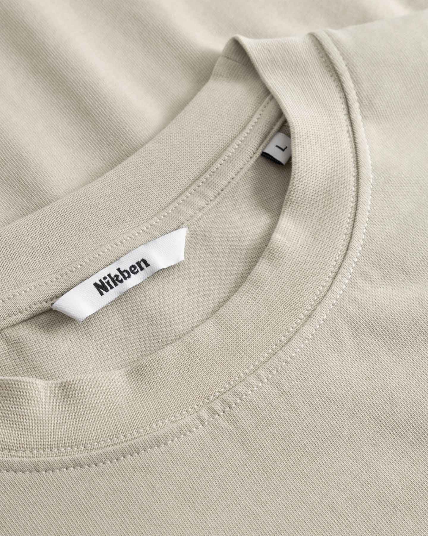 Close-up of a beige t-shirt with a brand label on the collar.
