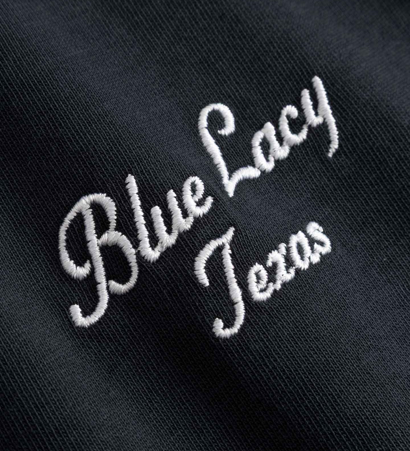 Close up of embroidered text 'Blue Lacy Texas' on  black t-shirt