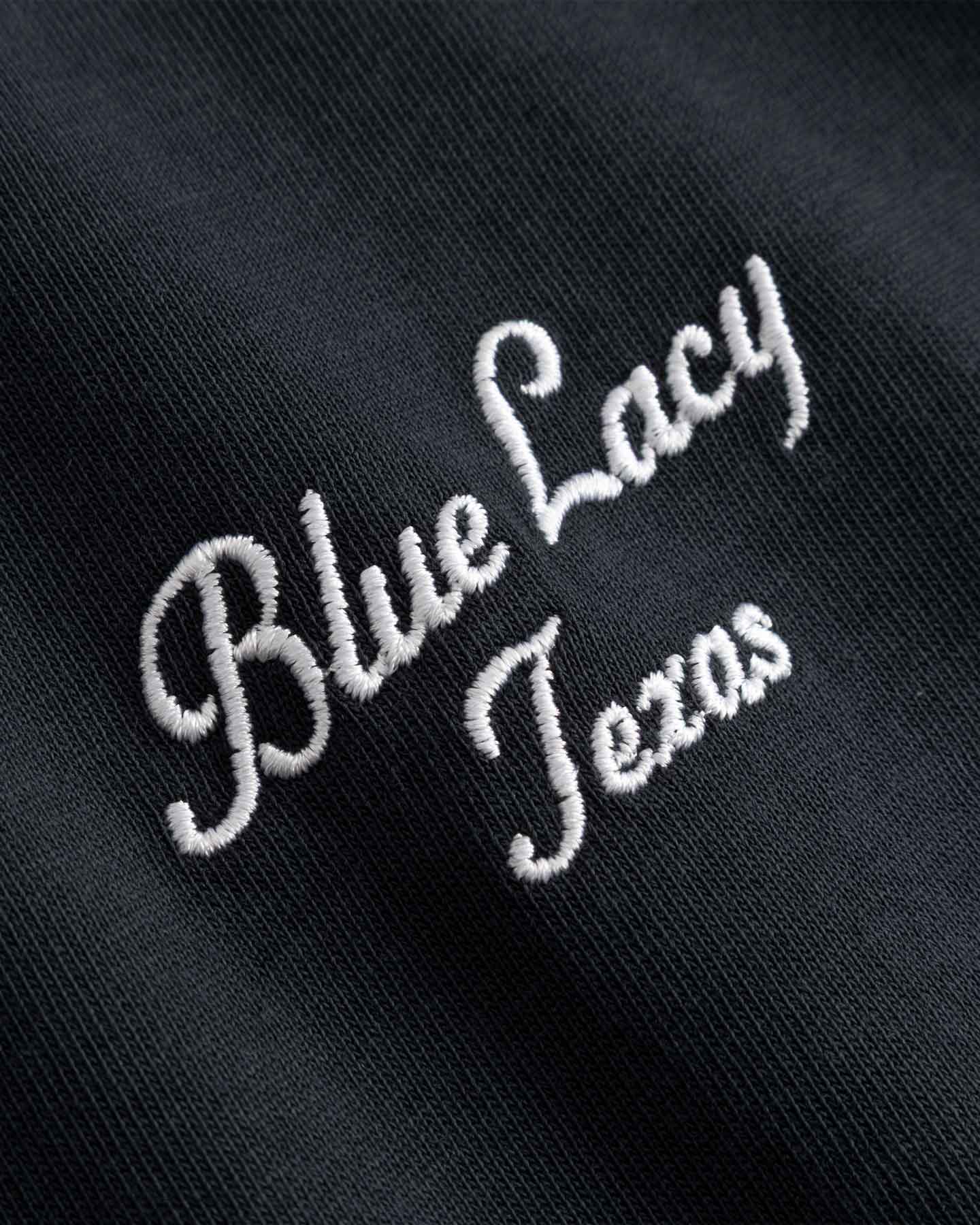 Close up of embroidered text 'Blue Lacy Texas' on  black t-shirt