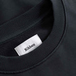 Close-up of a black sweater with a white label displaying 'Nikben' 