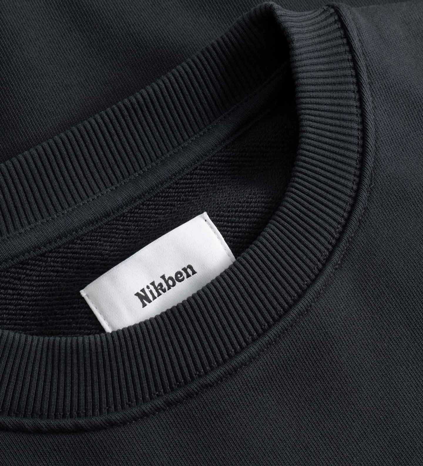 Close-up of a black sweater with a white label displaying 'Nikben' 