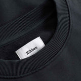 Close-up of a black sweater with a white label displaying 'Nikben' 