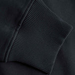 Close-up of a black sweatshirt with ribbed cuffs and hem.