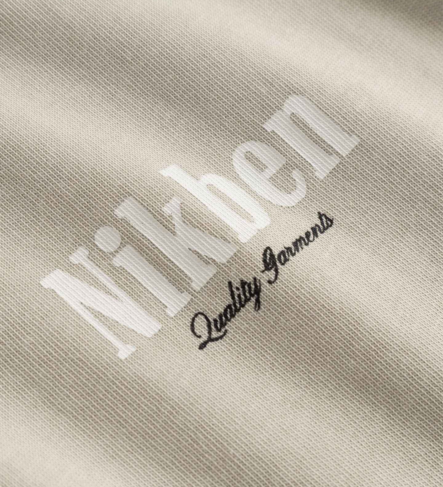 Close up of small logo on beige t-shirt