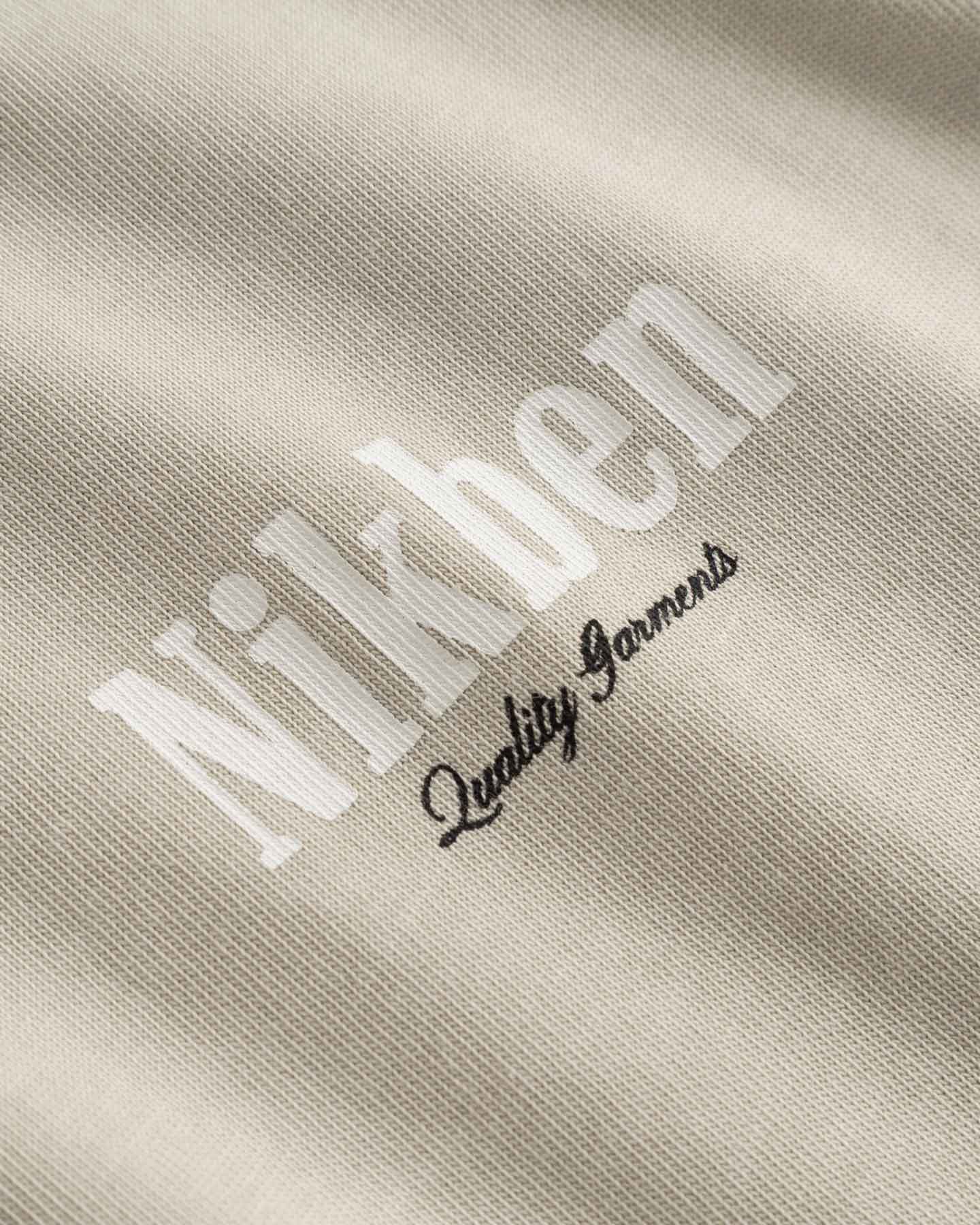 Close up of small logo on beige t-shirt