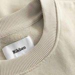 Close-up of beige sweater with a 'Nikben' label.