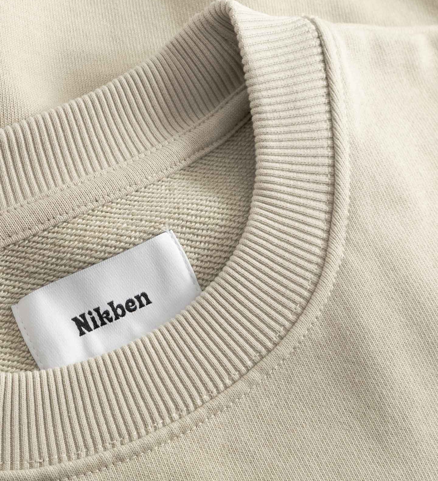 Close-up of beige sweater with a 'Nikben' label.