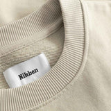 Close-up of beige sweater with a 'Nikben' label.