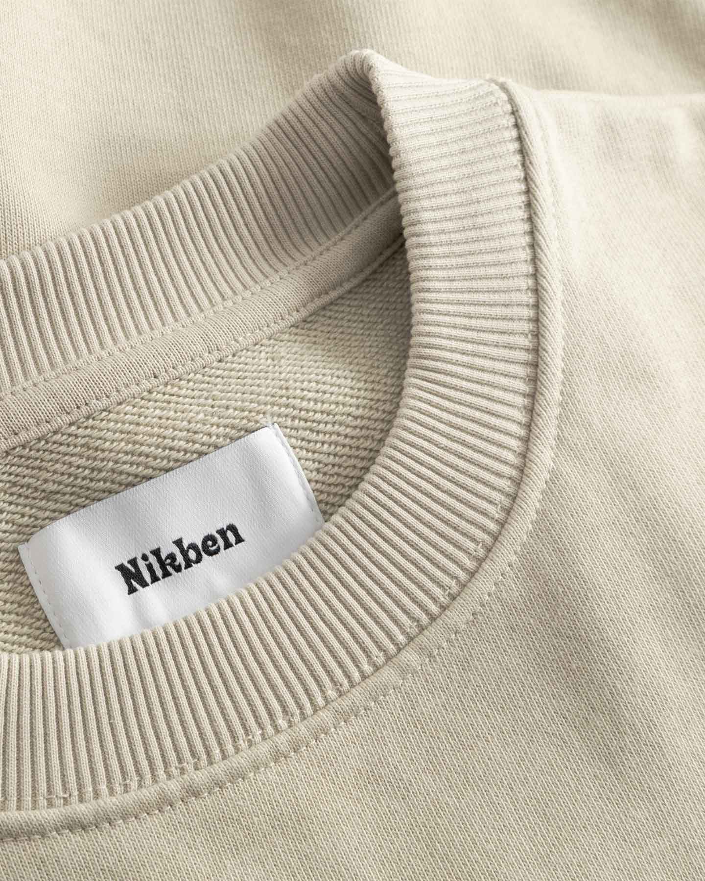 Close-up of beige sweater with a 'Nikben' label.
