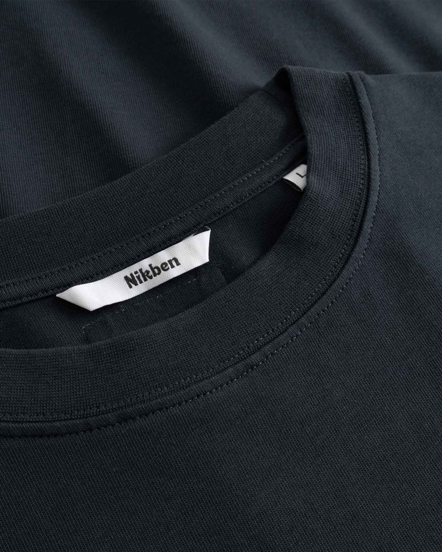 Close-up of a black t-shirt with a visible brand label on the collar.