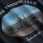 Close up of Black t-shirt with desert scene and 'Texas Tanning Club' text 