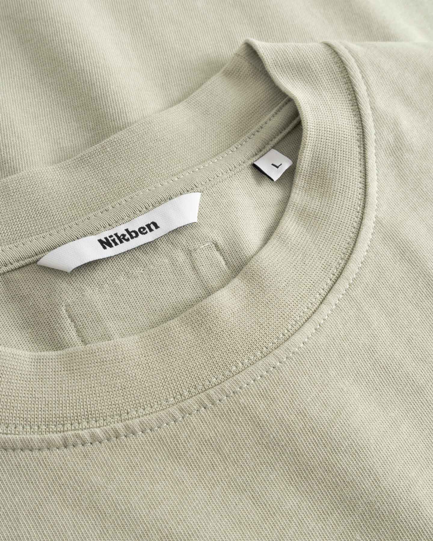 Close-up of a beige t-shirt with a brand label in the collar.