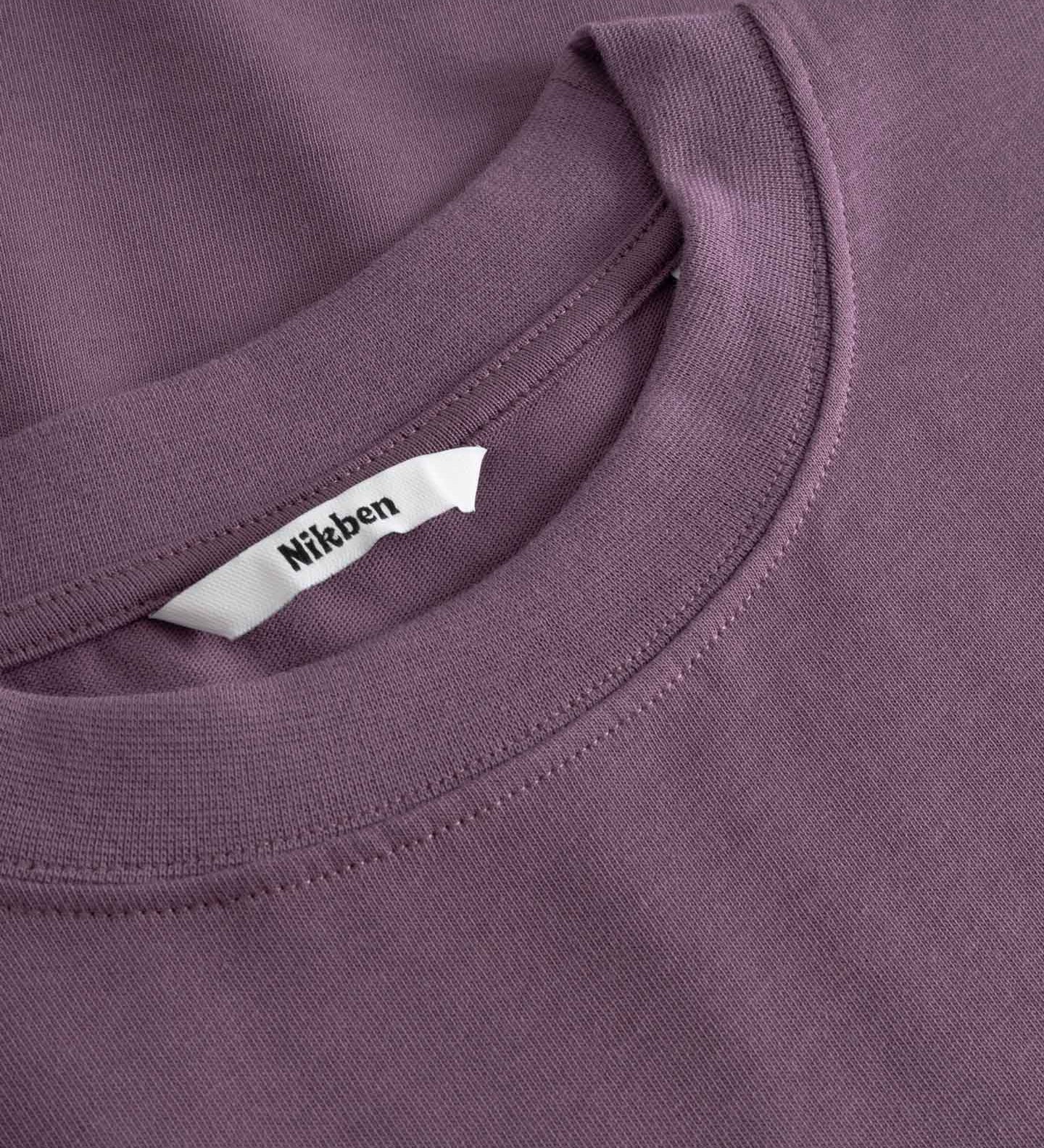 Close-up of a purple t-shirt with a brand label on the collar.