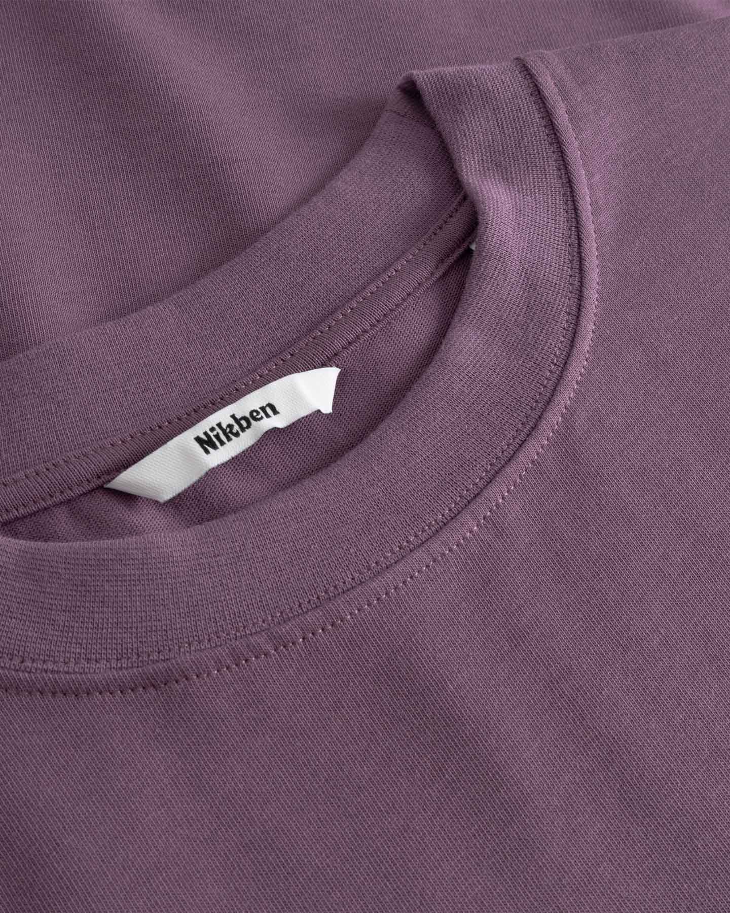 Close-up of a purple t-shirt with a brand label on the collar.