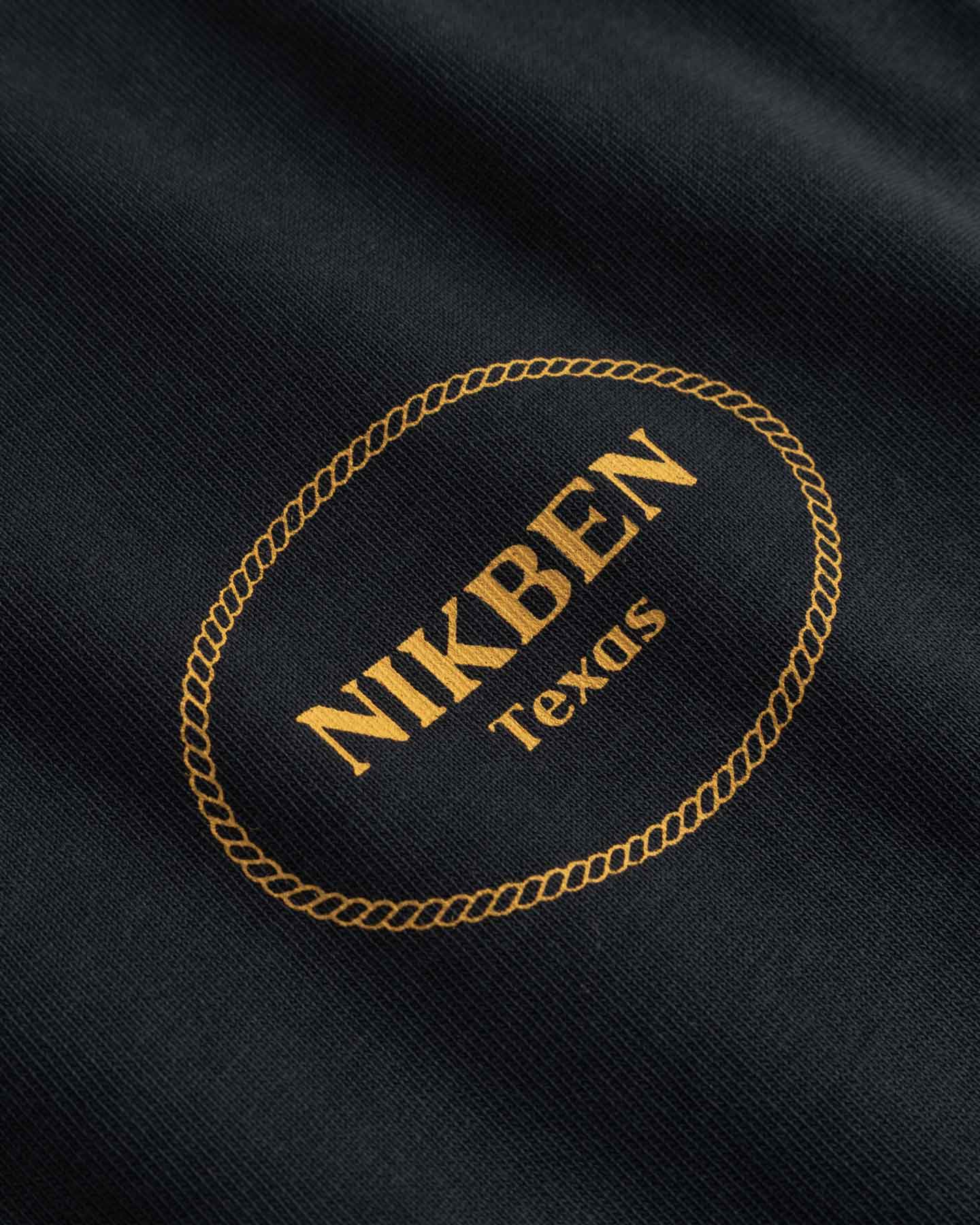 Close Up Of Small Yellow Logo on chest of Black - T-shirt 