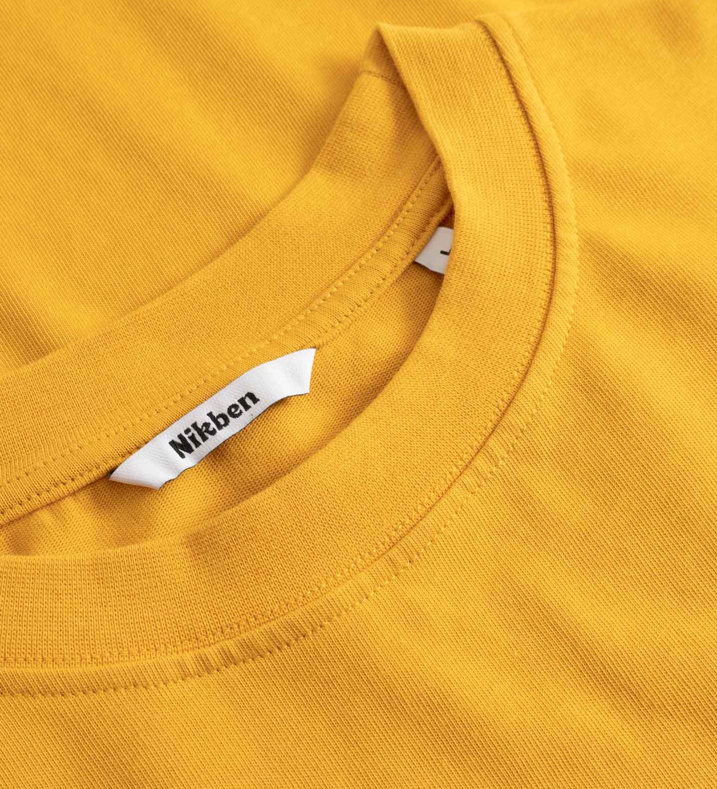 Close-up of a yellow shirt with a visible brand tag.