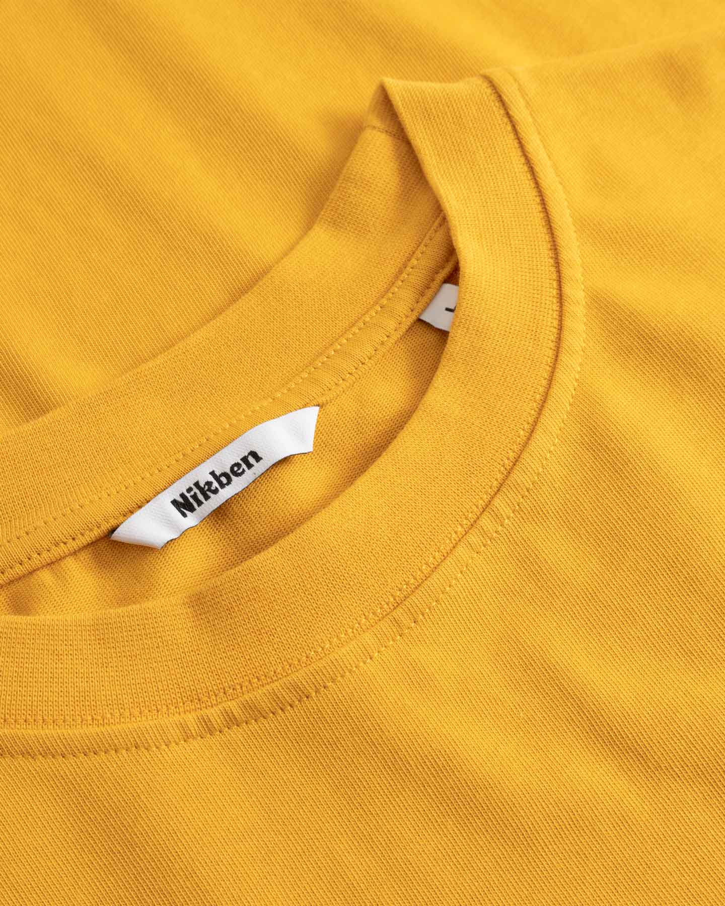 Close-up of a yellow shirt with a visible brand tag.