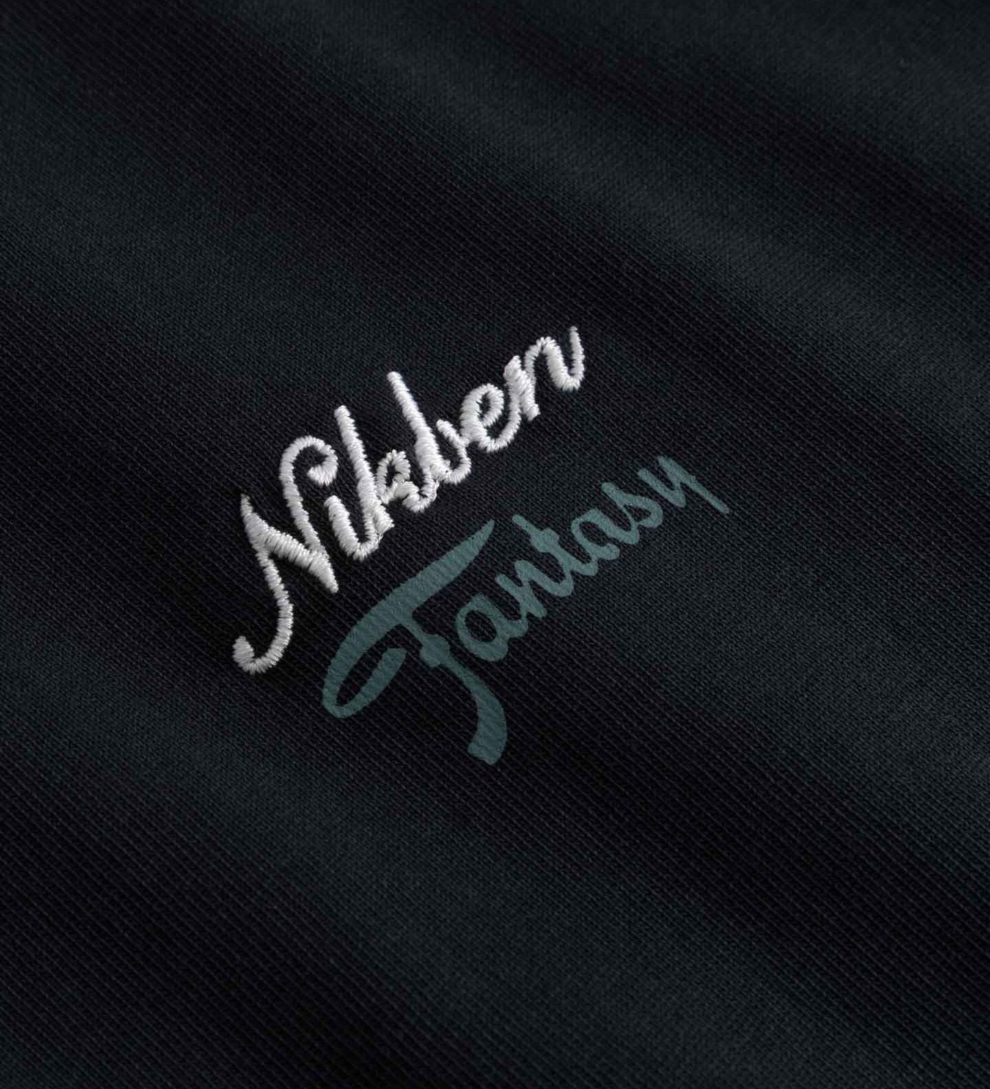 Close up of Embroidered text 'Nikben Fantasy' on a black fabric 