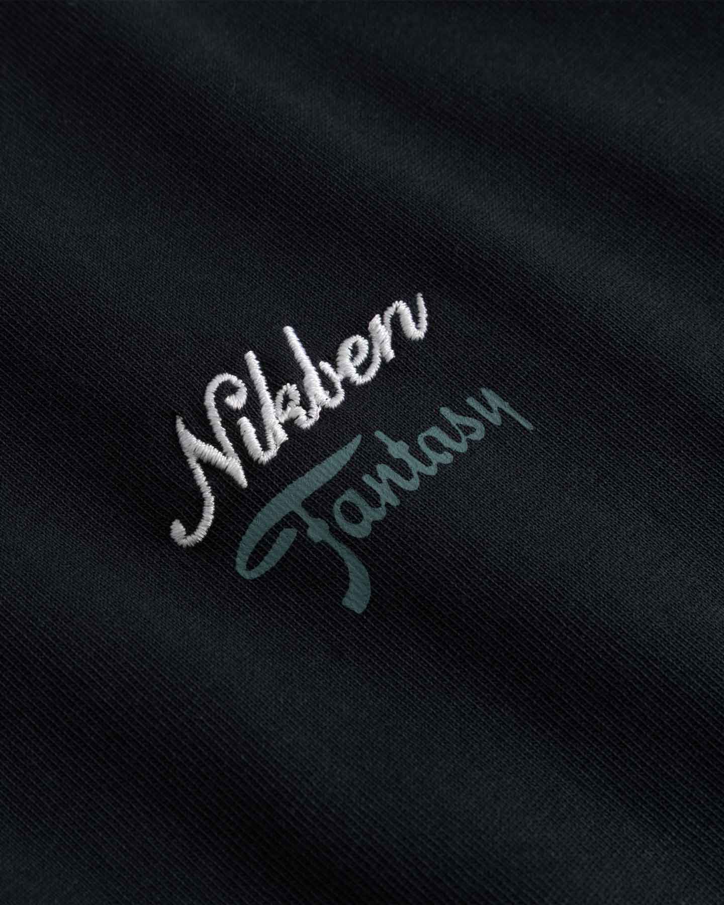 Close up of Embroidered text 'Nikben Fantasy' on a black fabric 