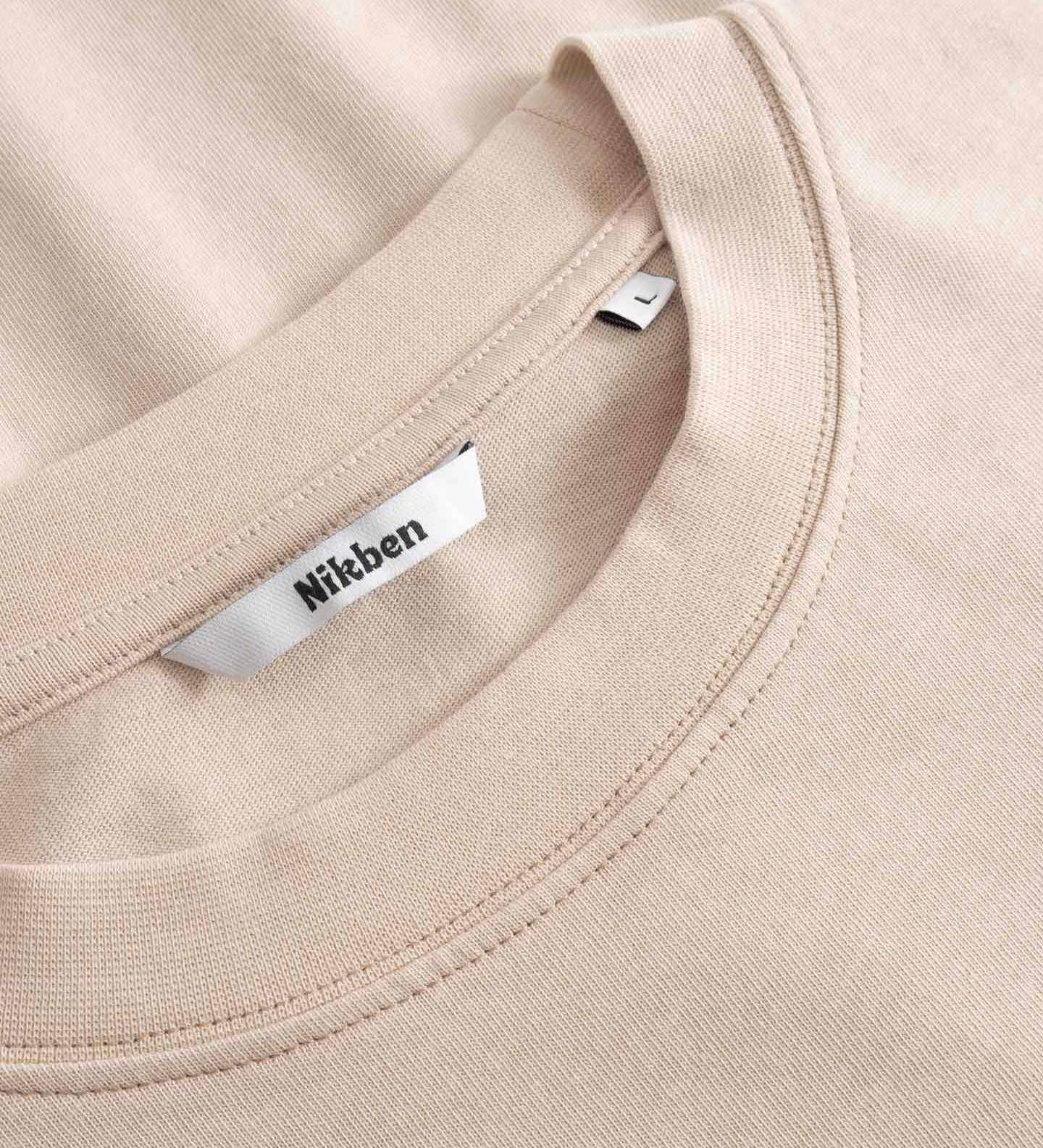 Close-up of a beige t-shirt with a Nikben label on the collar.