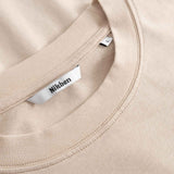 Close-up of a beige t-shirt with a Nikben label on the collar.