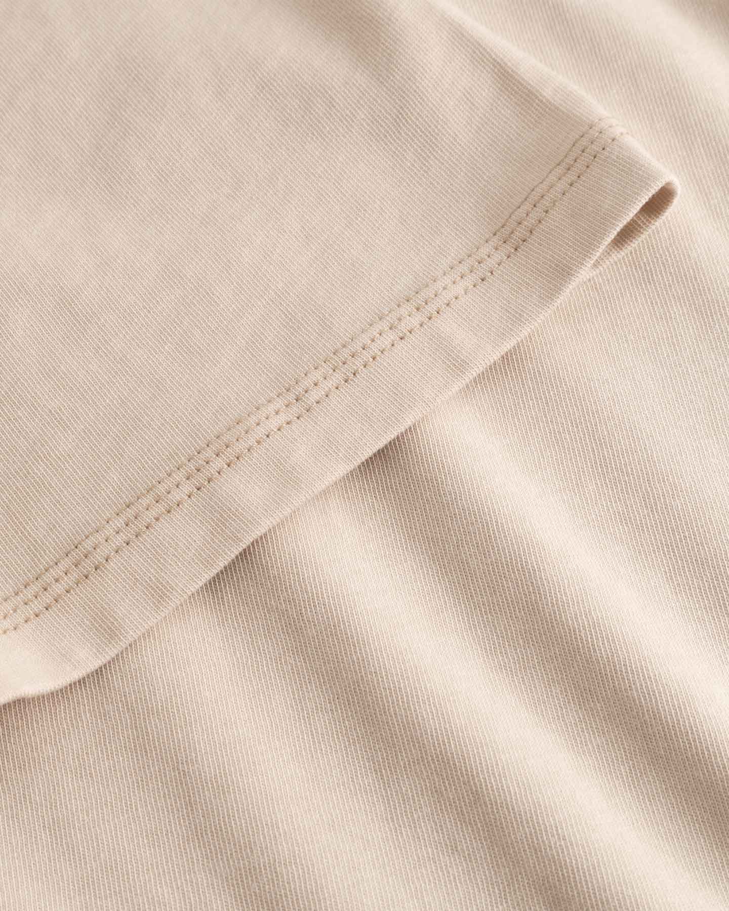 Close-up of beige fabric with a focus on texture and stitching.
