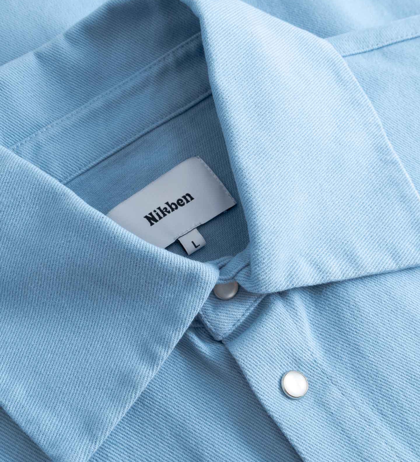 Close-up of a light blue long sleeved shirt with visible Nikben label inside the collar.