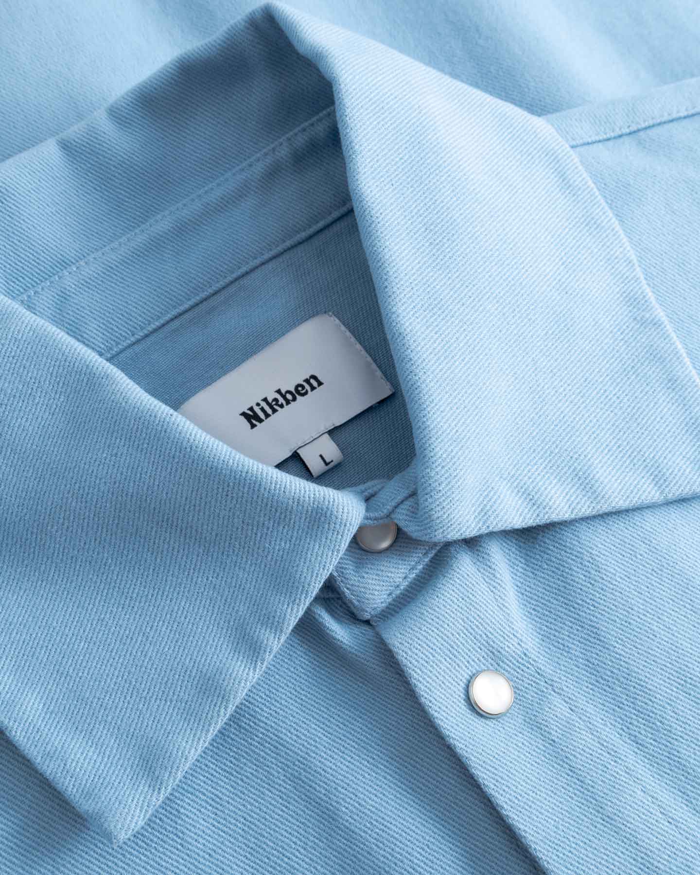 Close-up of a light blue long sleeved shirt with visible Nikben label inside the collar.