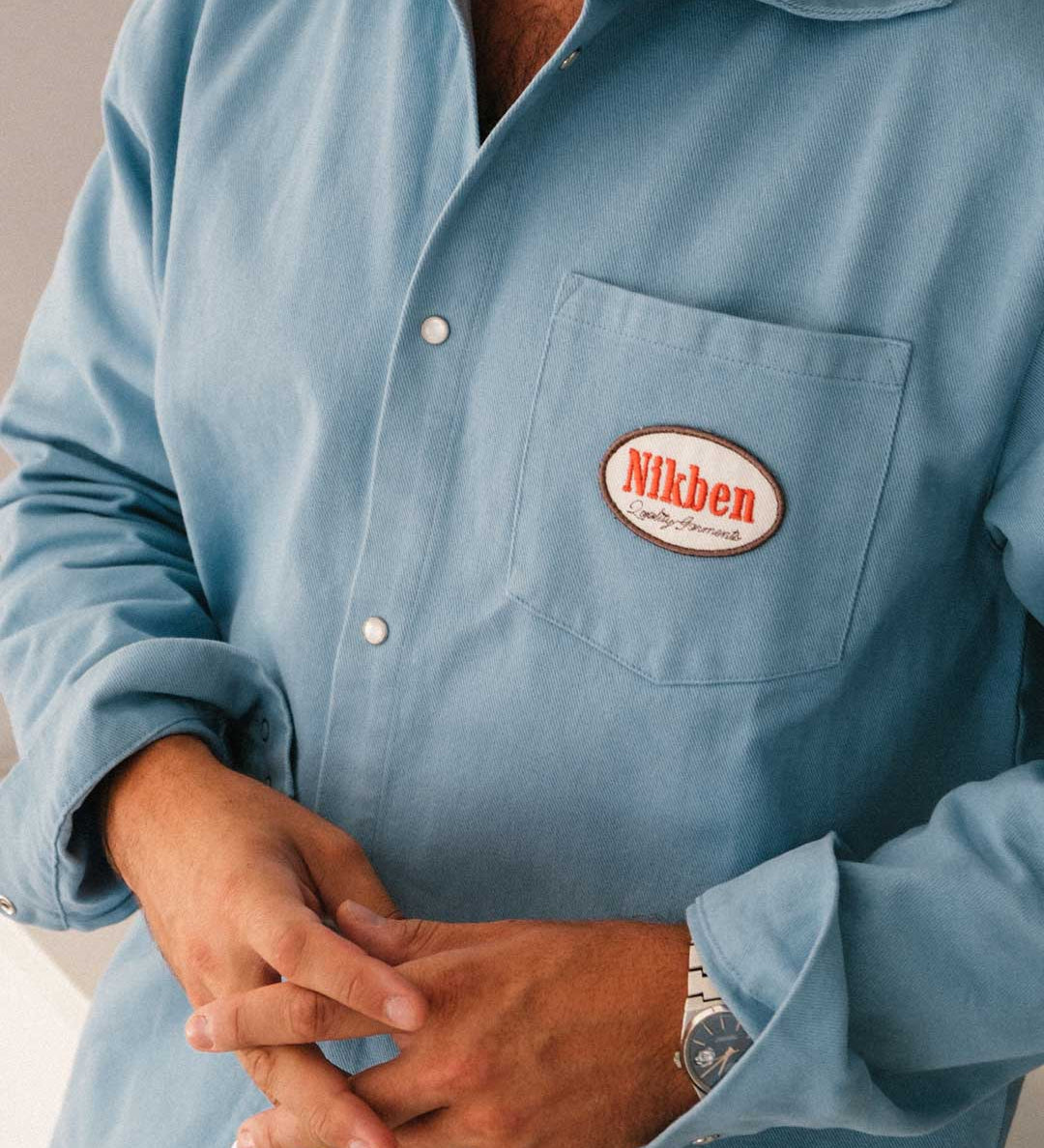 model wearing  blue overshirt with a 'Nikben' logo on breast pocket
