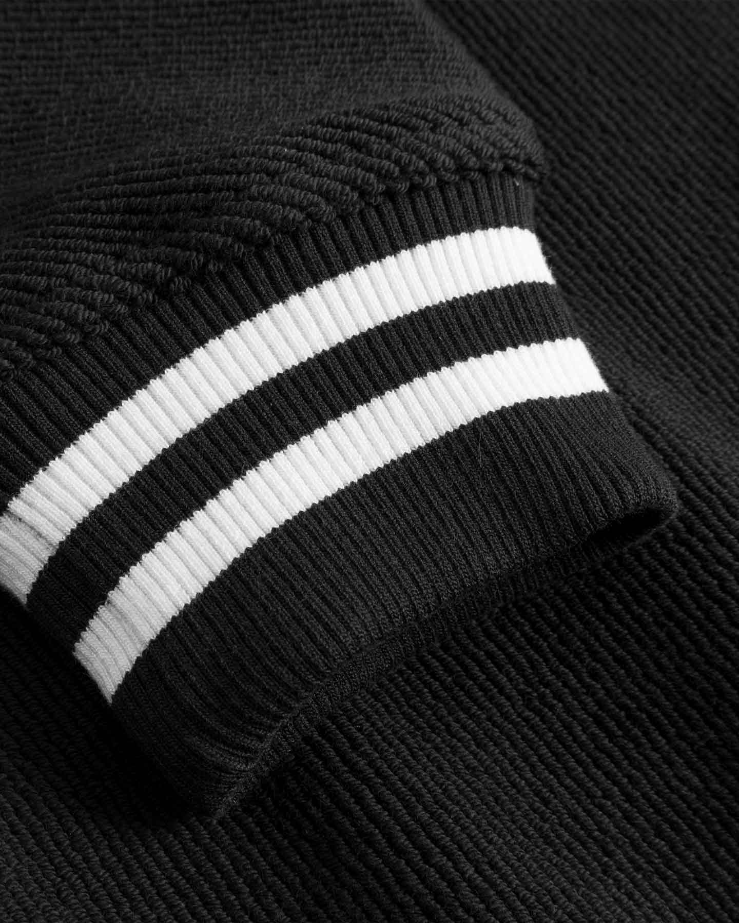 Close-up of sleeve with white stripes on black bomber jacket