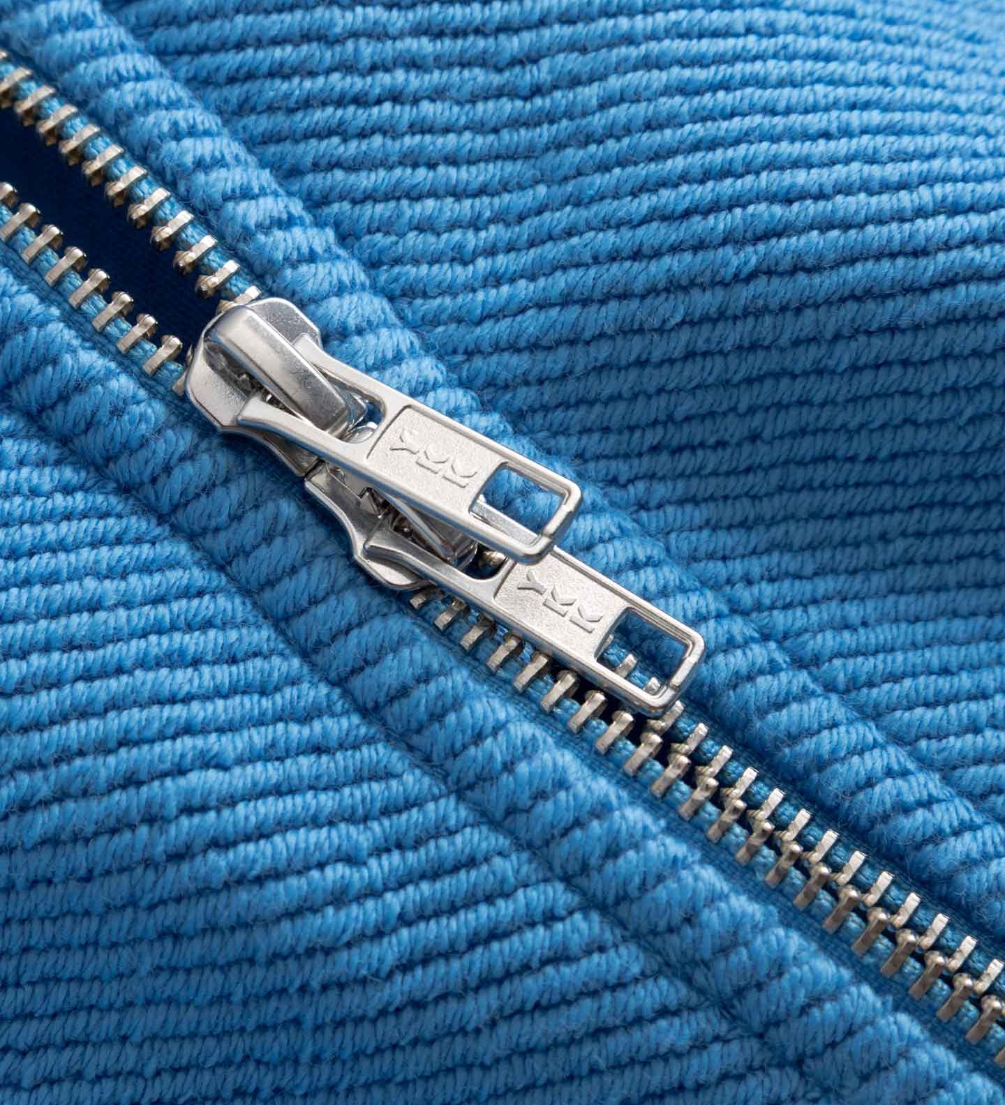 Close-up of a silver double zipper on blue fabric