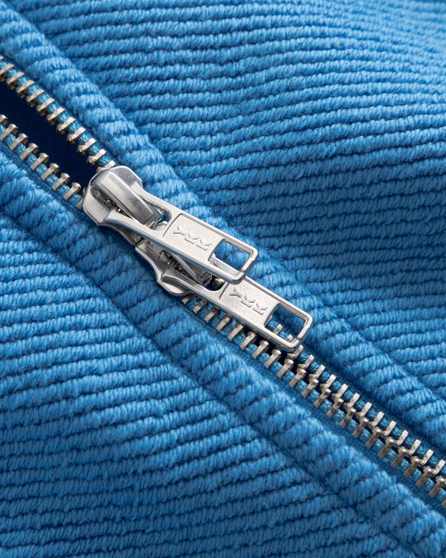 Close-up of a silver double zipper on blue fabric