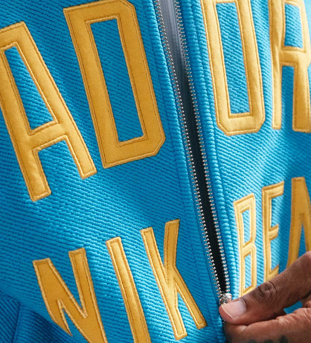 close up of material and yellow text on blue bomber jacket