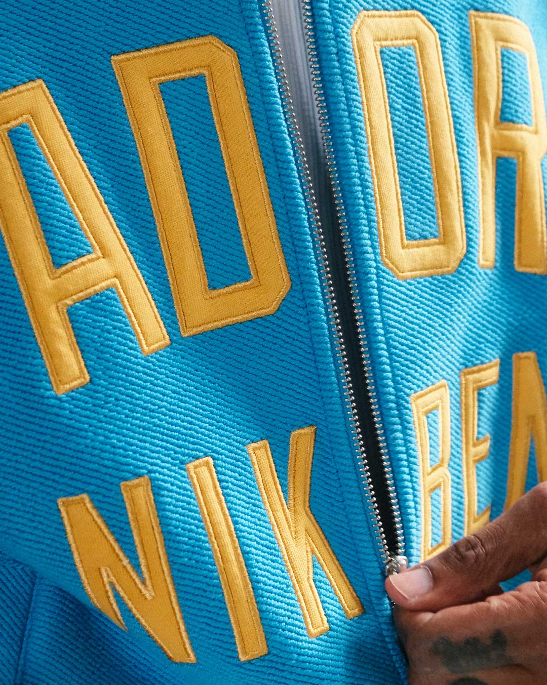 close up of material and yellow text on blue bomber jacket