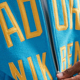close up of material and yellow text on blue bomber jacket